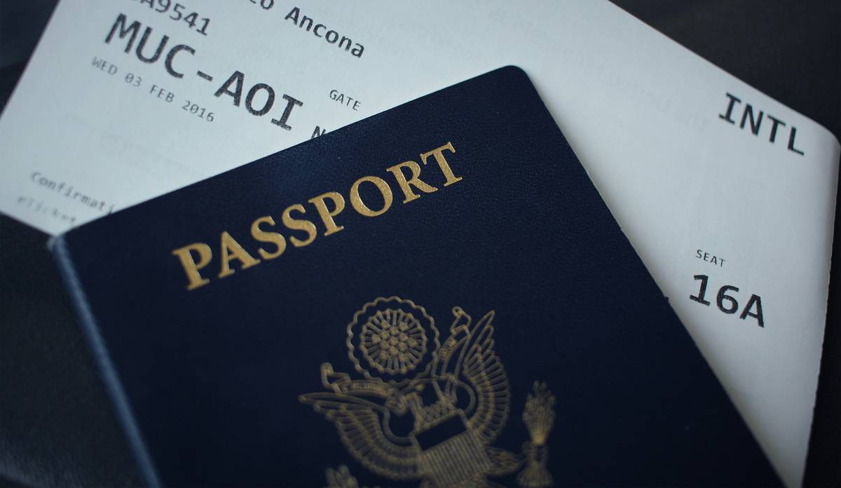 Traveler reviewing last-minute cancellation shield policy documents on phone at airport gate