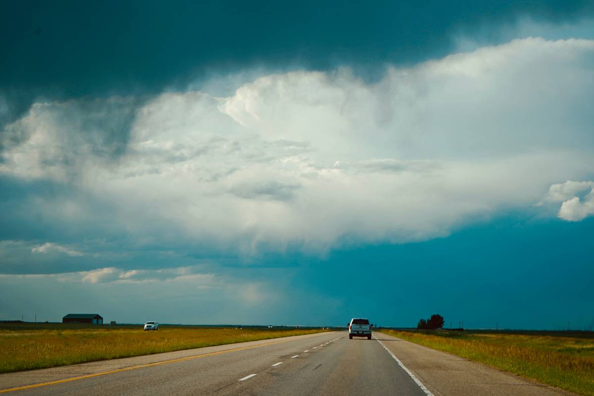 Passenger waiting at airport during storm with luggage, illustrating weather related travel protection needs