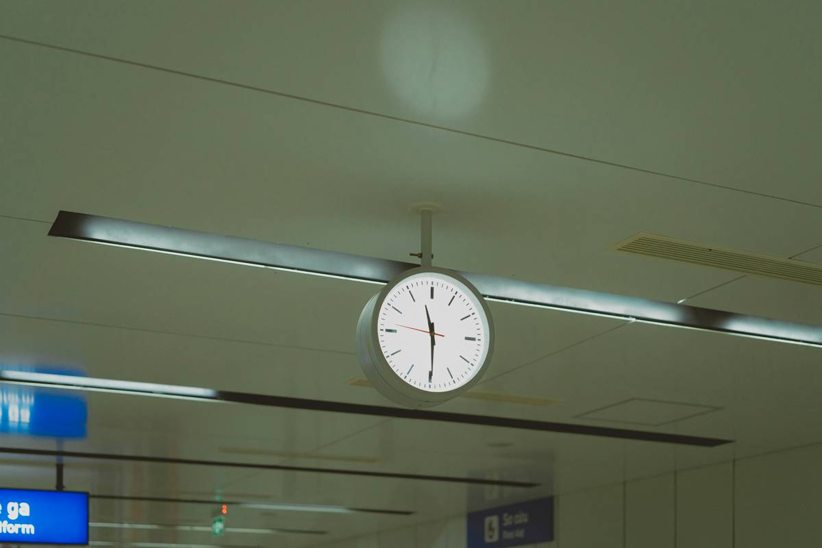 Traveler waiting at airport gate with luggage, holding boarding pass and phone showing flight delay alert – delayed flight insurance policy in action